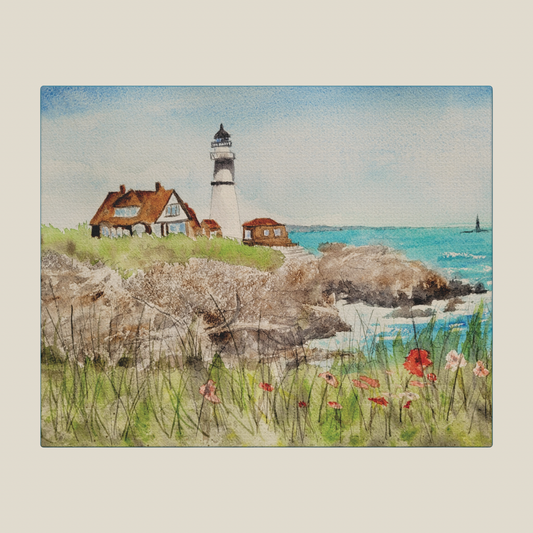 Lighthouse on a rocky shore with houses and flowers in the foreground